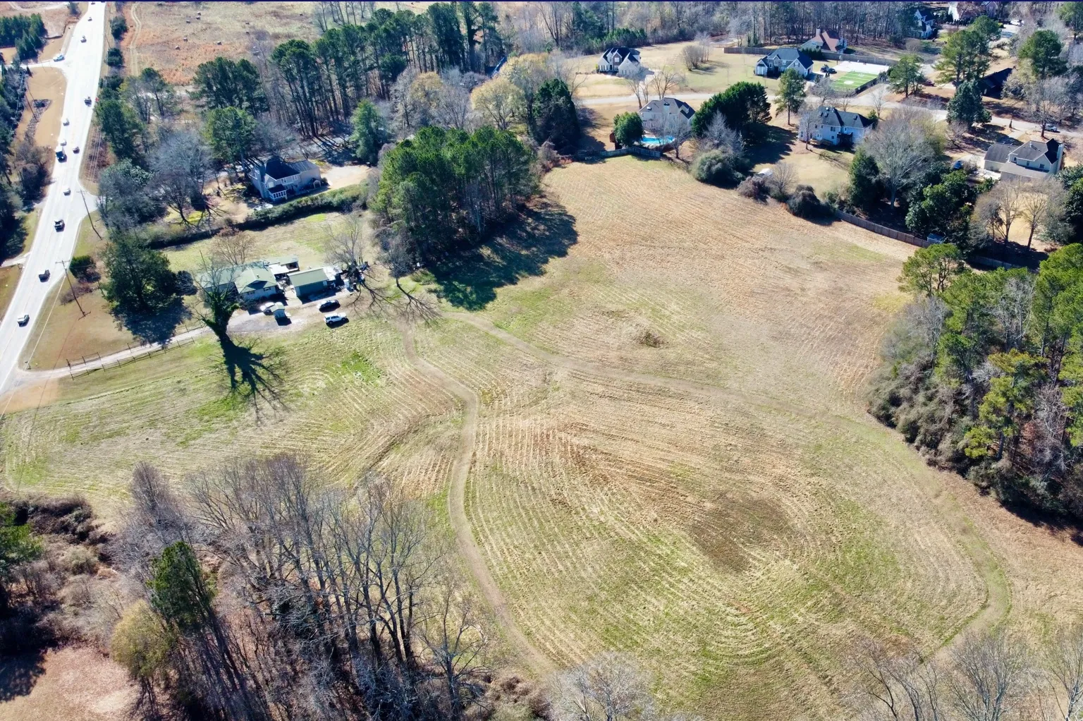 Drone photo of a 10.9 acre Res2 zoned tract at 6956 Post Road in Cumming, Forsyth County, Georgia: open pasture with a tree line and road frontage